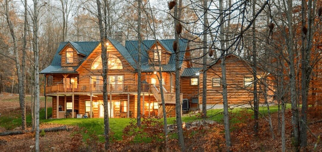 photo of three story log home in heavily wooded log